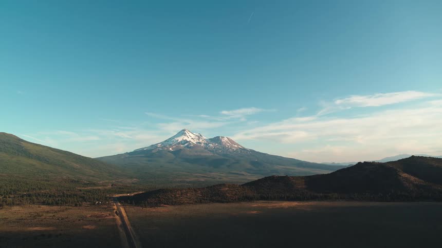 An open field gives way to rolling hills and a snow capped mountain