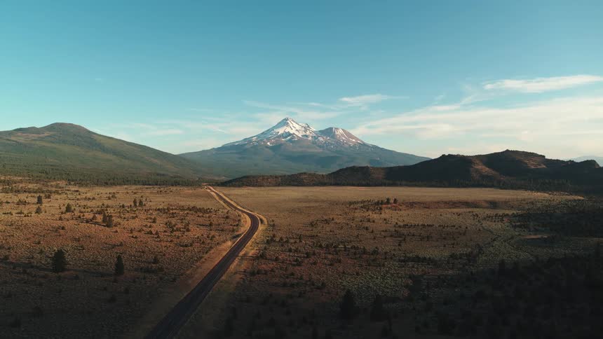 Car driving on a road on the plains near the mountains at morning