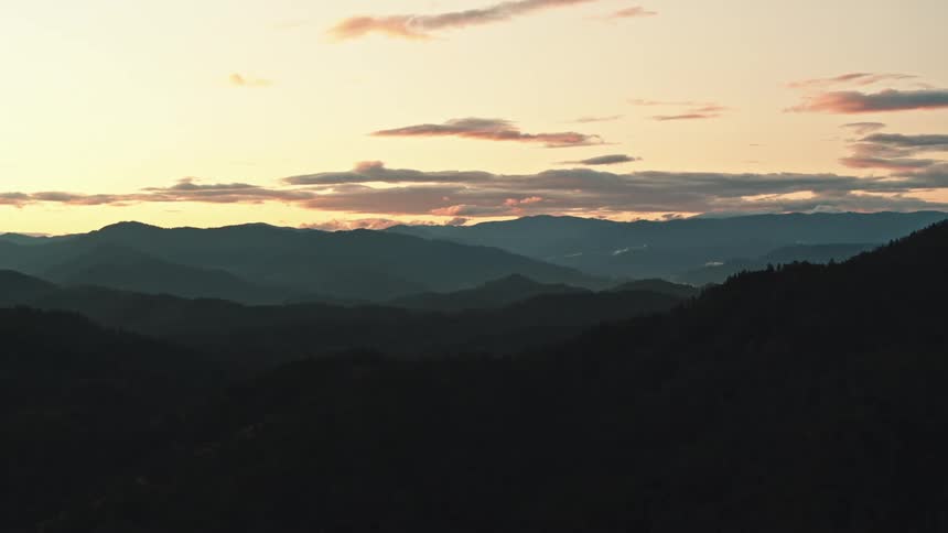 A landscape with a mountain range with the sky and clouds in the background