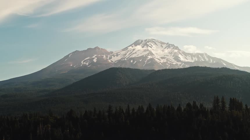 Aerial view of high snowy mountain with forest silhouet