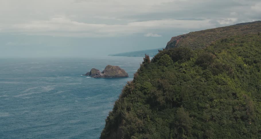 A tree and brush covered ridge overlooking the ocean and a small rock island