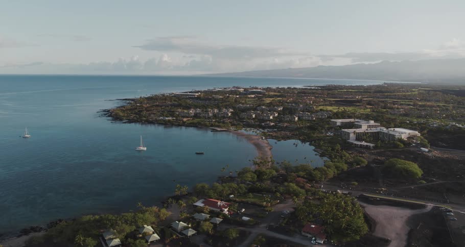 Boats sail in the ocean near dense neighborhoods