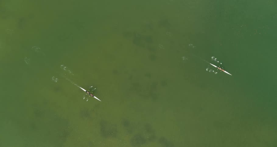 Two kayaks are traveling on water and each boat has two people inside rowing
