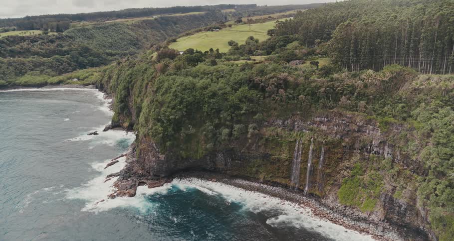 A coast with a cliff with waterfalls with the sky and clouds in the background