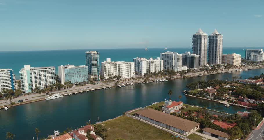 Street vehicles and buildings near the coast with the ocean sky and clouds in the background