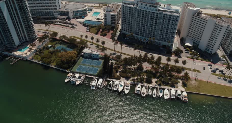 Yachts are moored near street across from apartment buildings and hotels