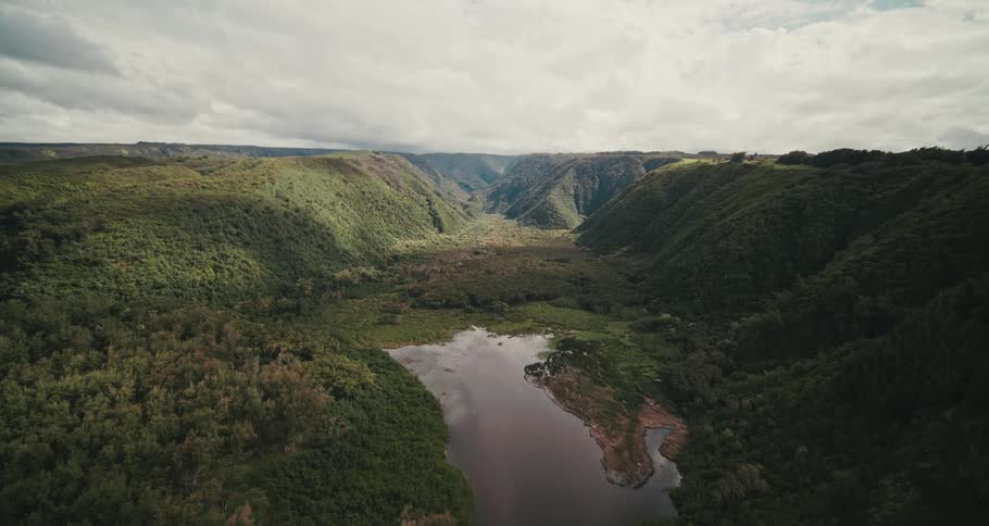 A narrow valley between mountains covered in vegetation on a cloudy day