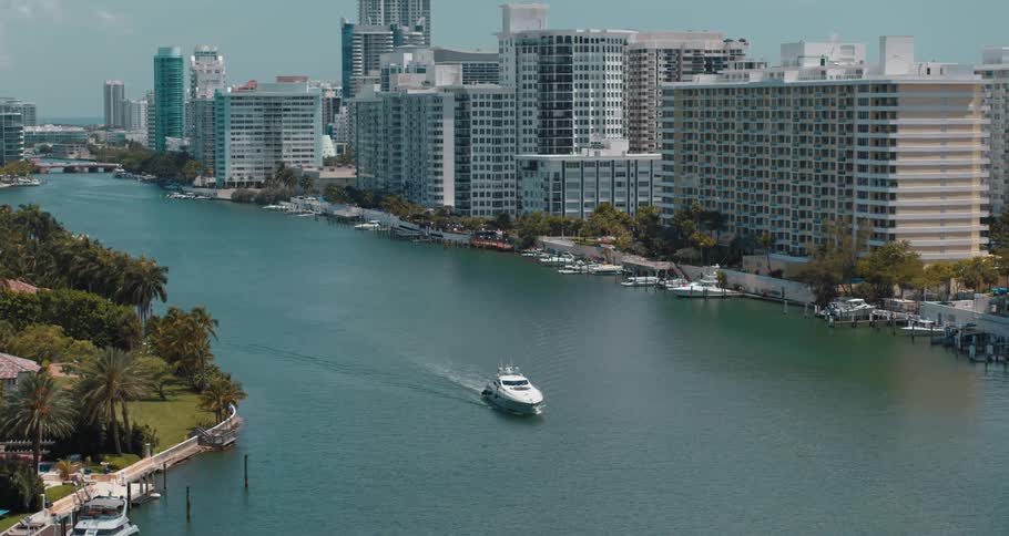 Aerial view of a boat on a river next to the skyline of a waterfront city