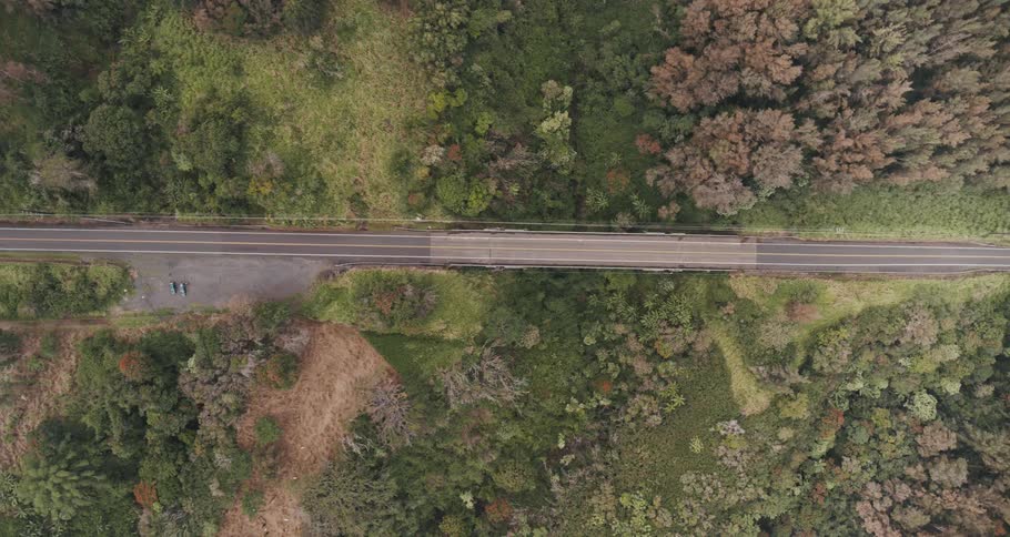 Two vehicles sit parked on the shoulder of a rural highway