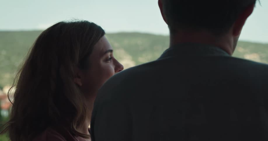 A man and woman are affectionate with each other as they look over a town
