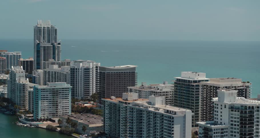 Tall buildings on a strip of land next to the ocean in a metropolis during the day