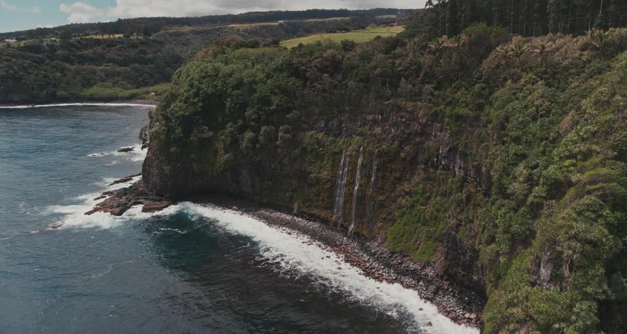 Aerial shot of waterfalls going into an ocean