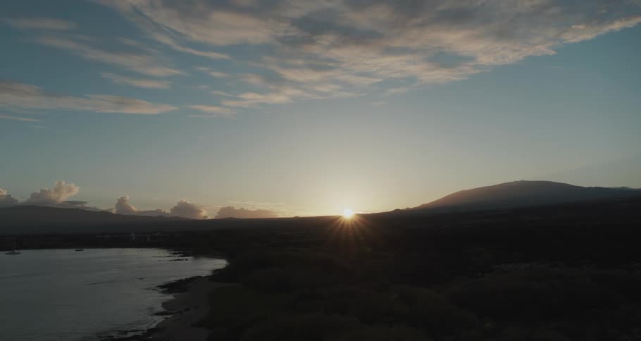 Sun rises on the horizon past hill and lake