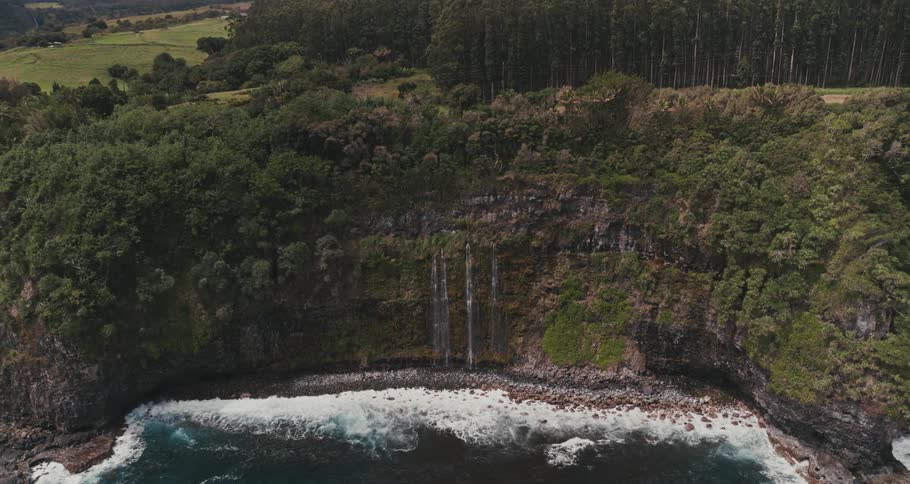 Aerial view of a waterfall pouring out a cliff near the coast