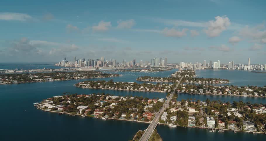 Islands with houses a bridge and trees with buildings the sky and clouds in the background