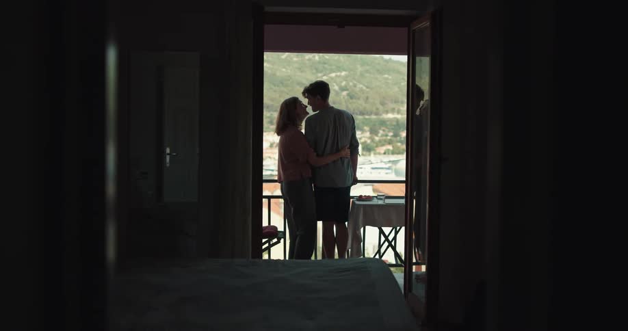 Young couple hug and kiss in the apartment balcony on a small town