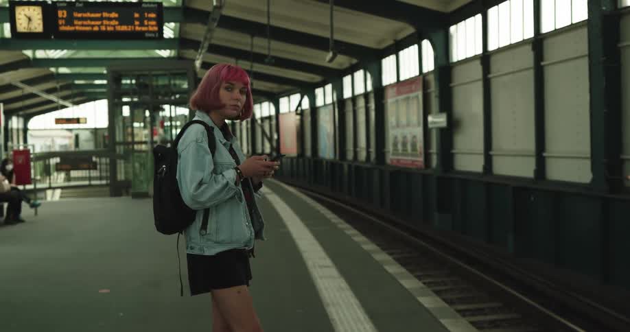 A woman looks for her train as she waits at the station