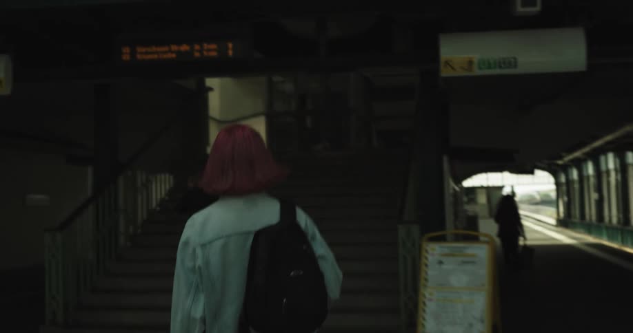 A woman leaves a subway station and walks up steps