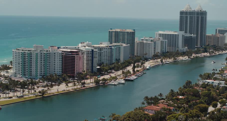 Boats travel in a canal between highrise buildings and neighborhood homes
