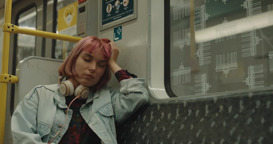 A woman with headphones sitting on a train