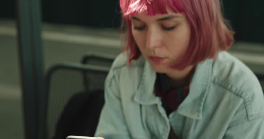 A woman is sitting on a bench looking at her cellphone