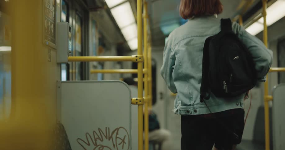 A woman putting books in a bag and getting off a train