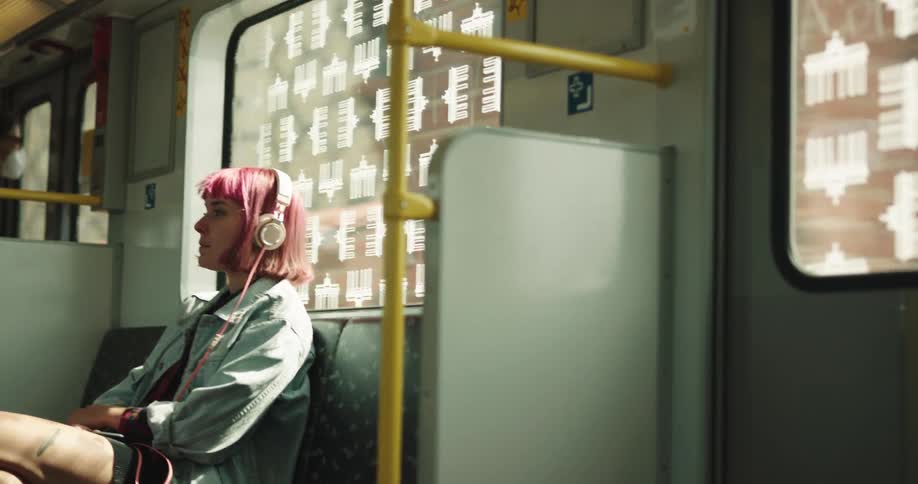 A woman with headphones sitting on a train