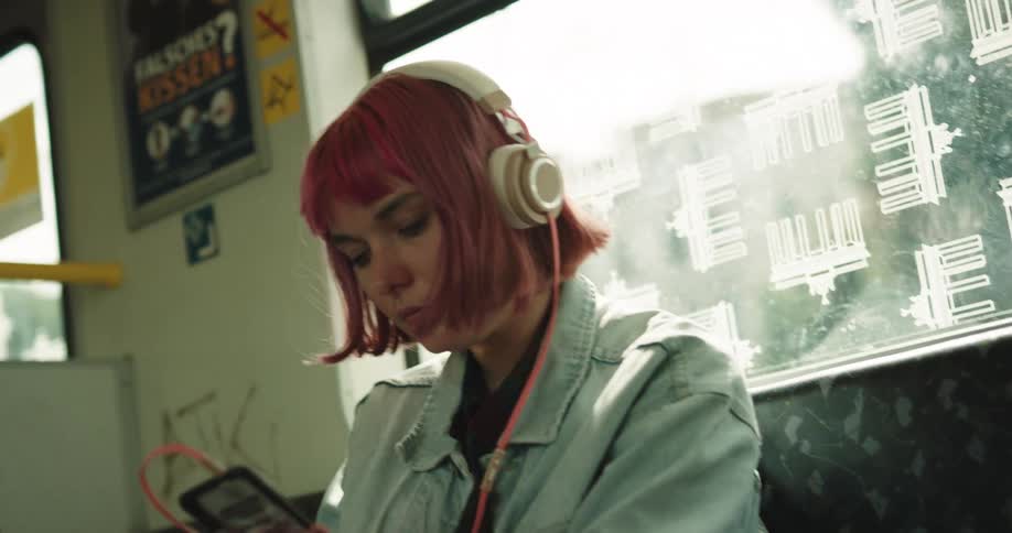 A woman puts on her headphones while riding a train