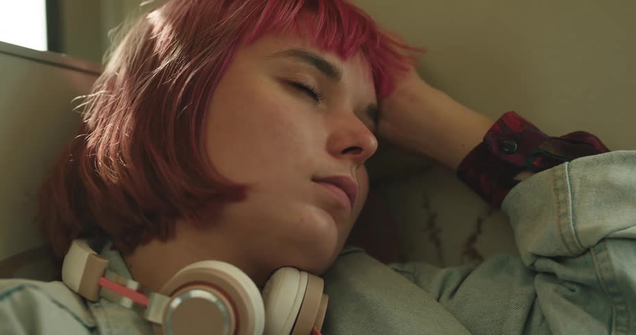 A young woman adjusts her position while sleeping on public transport