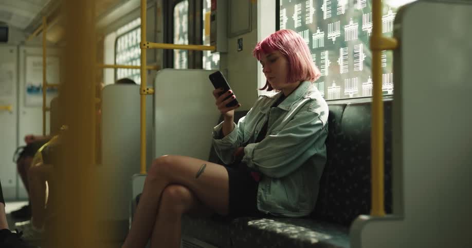 A woman sitting on a train holding her phone adjusts her short skirt