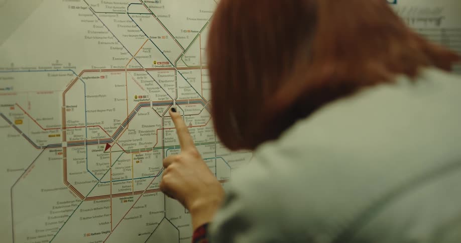 A woman runs her finger along a subway map on a board