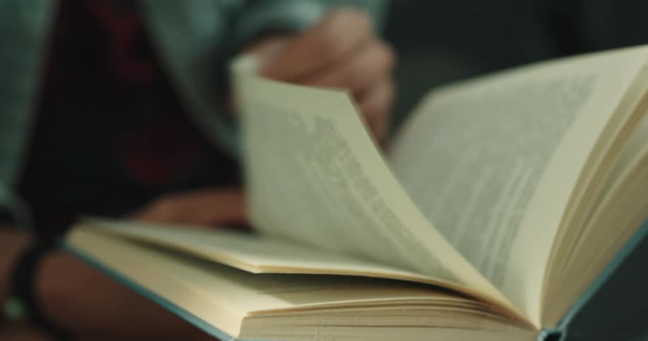A woman turns the page while reading a book