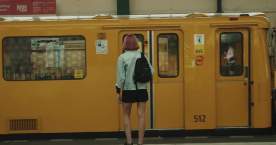 Young woman with short pink hair walking up the stairs of the train station