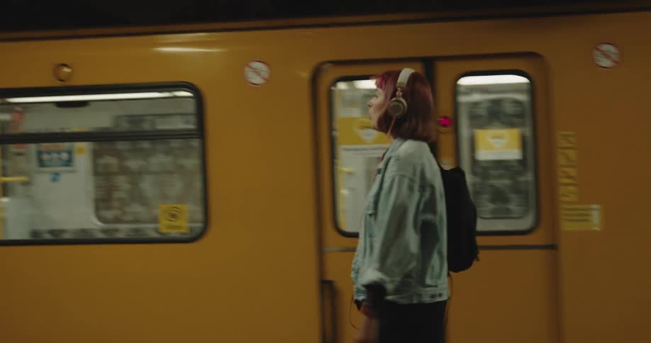 A woman is walking past the moving train in the subway