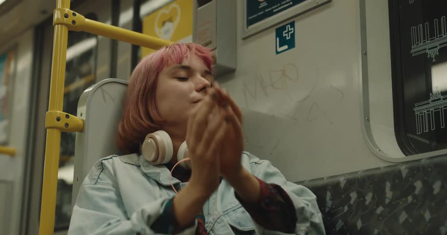 A young woman is yawning while sitting and riding on the subway