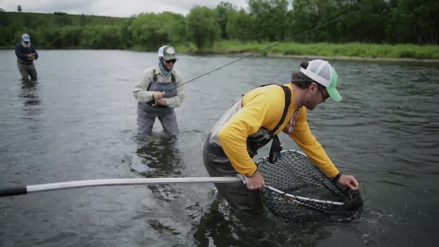 Men wade and fish in a river