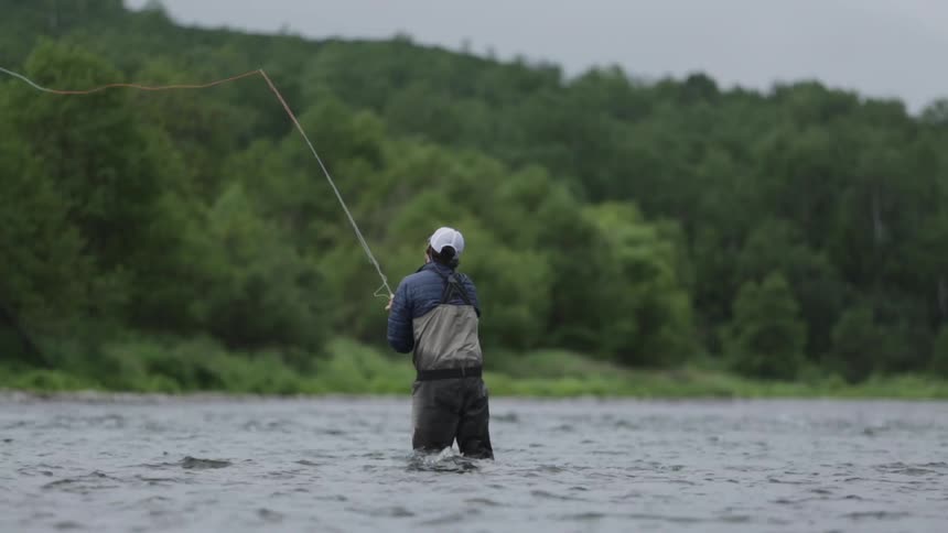 A man is fly fishing on a cloudy day