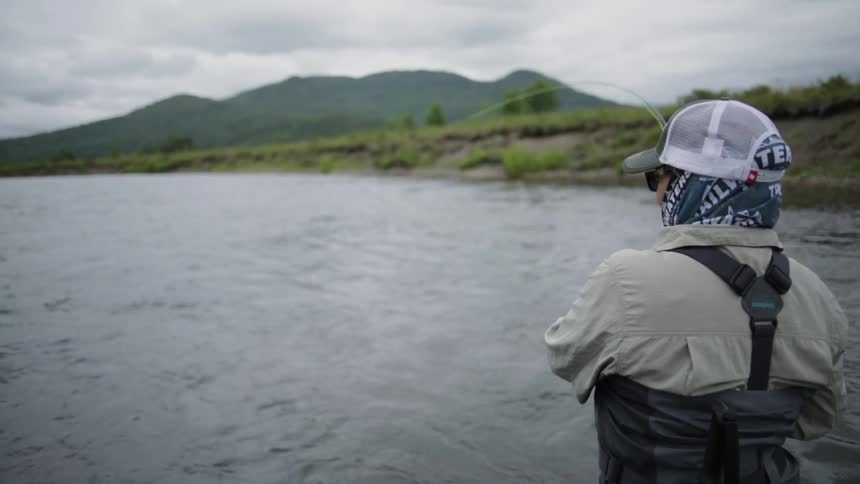 A person is fishing in a rough stream