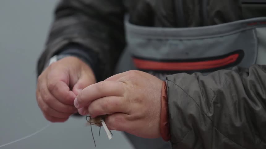 A man tying a fishing lure on fishing line