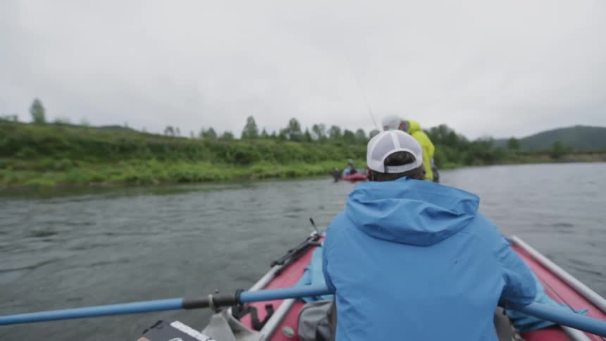 Men in row boats with fishing gear row toward a shore