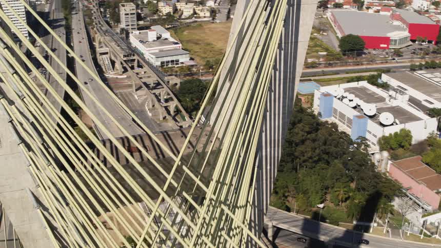 Cars travel around suspension bridge and highway around a big city