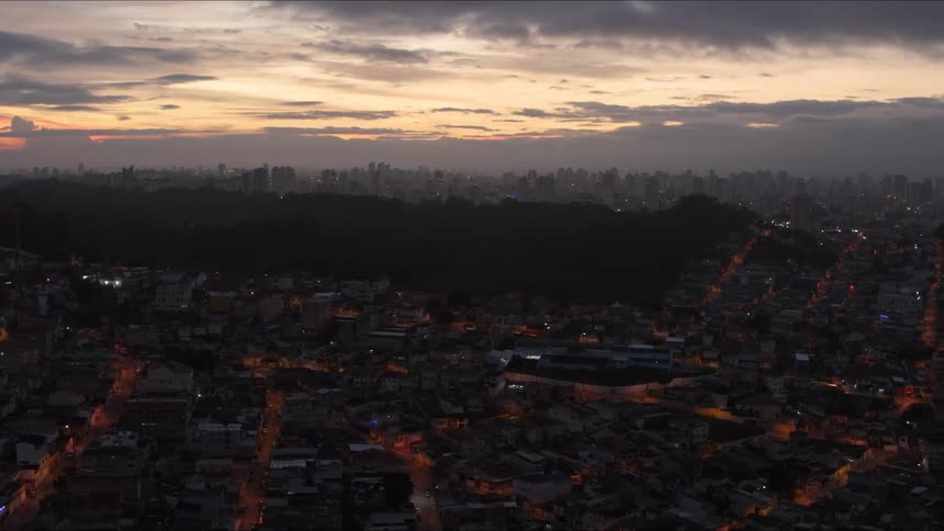 Lights come on in a dense suburb near downtown as day turns to night