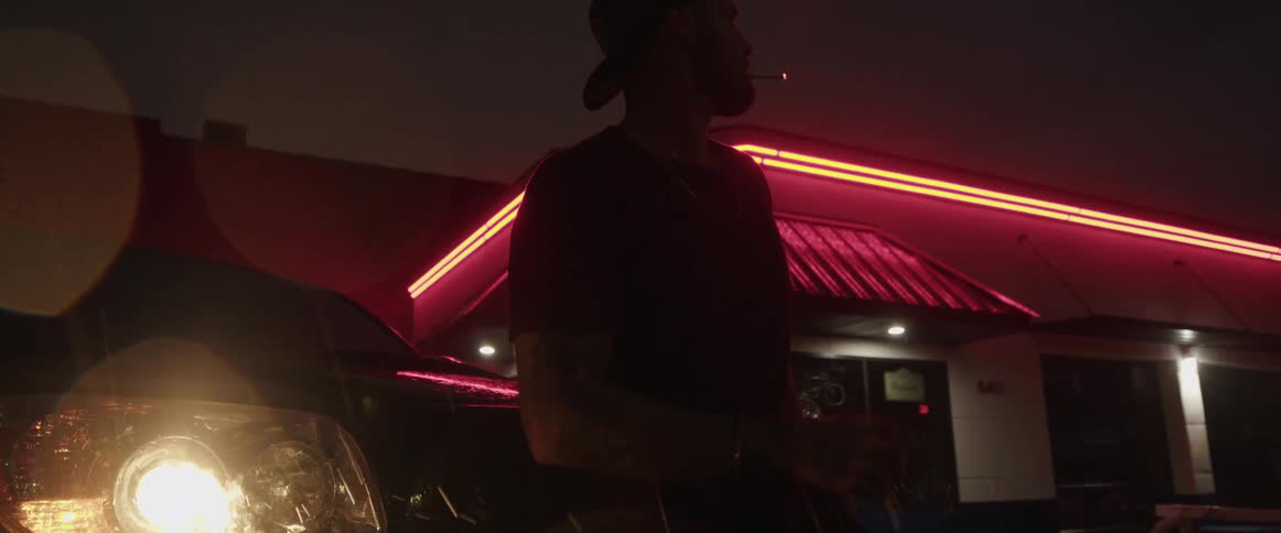 A man is smoking by her car in the rain at night