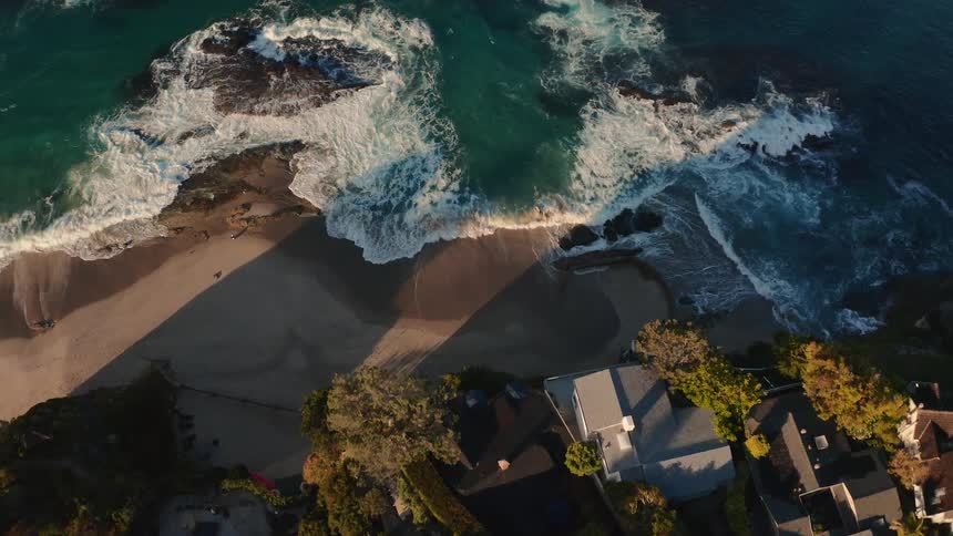Aerial view of waves crashing on beach with houses