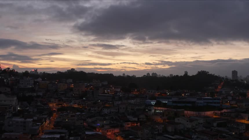 The tall buildings of a metropolis loom in the distance from the dimly lit slums
