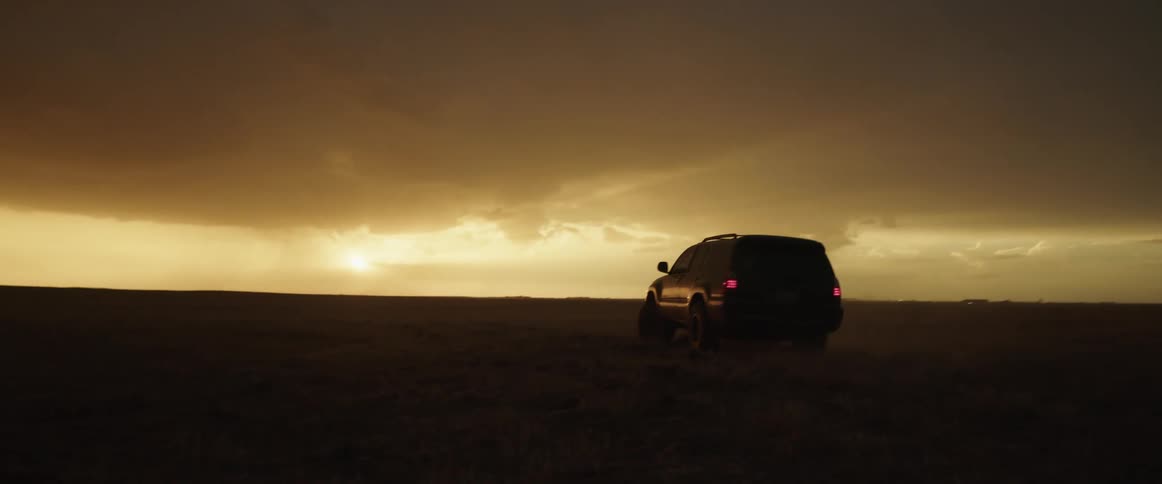 A sport utility vehicle drives in a semi circle in a dirt field