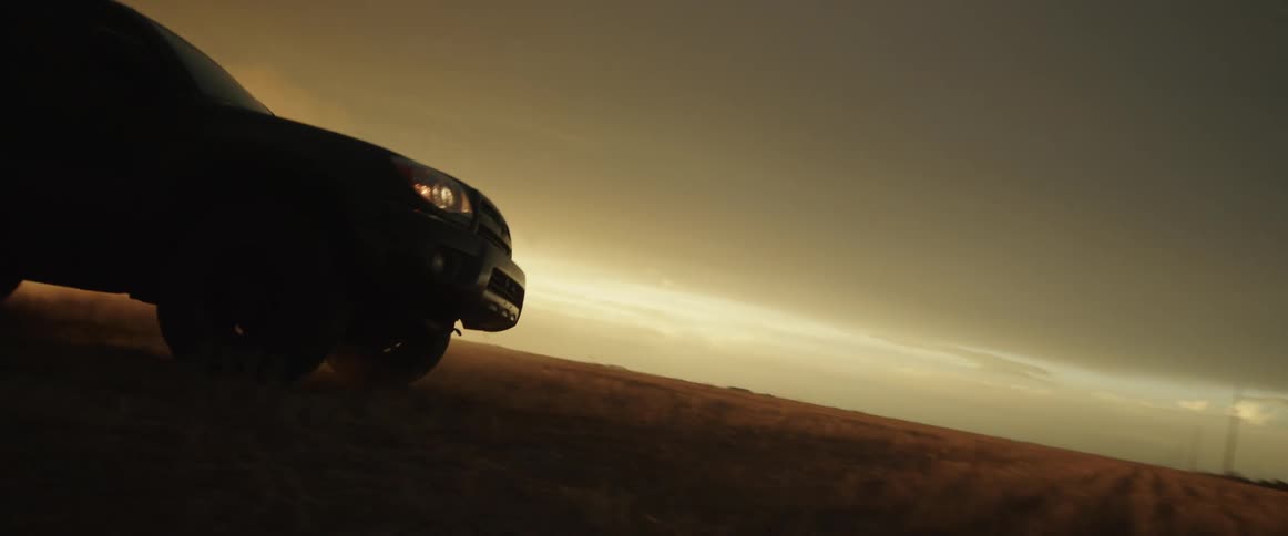 A sport utility vehicle weaves back and forth as it drives through an open field