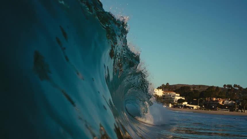 An ocean wave is flowing over onto the beach near a coastal city