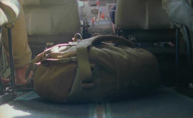 A backpack sits on the floor behind seats as sunlight shines on dust in the air