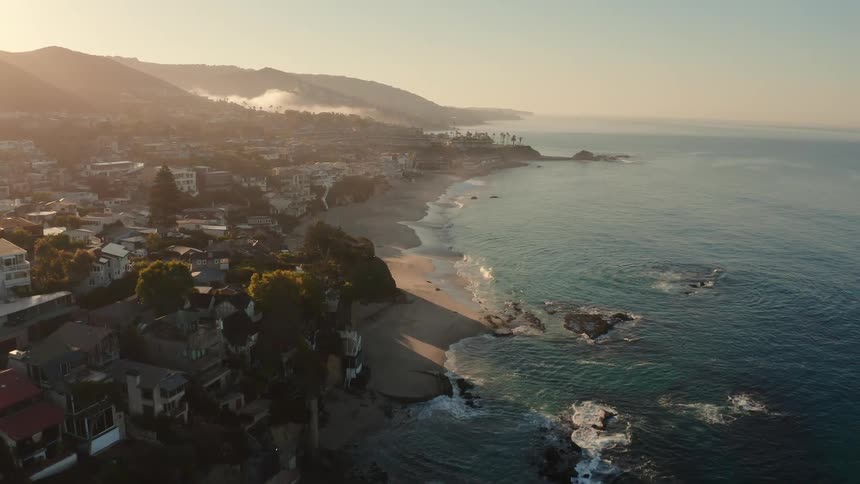 An aerial view of a coastal town and beach early in the morning